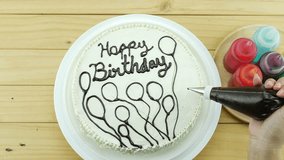 Woman is drawing chocolate on top of birthday butter cake decoration 