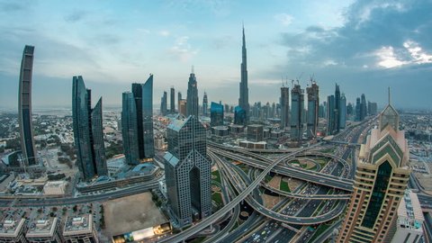 View on modern skyscrapers and busy evening highways day to night transition timelapse in luxury downtown of Dubai city. Top aerial view from tower rooftop. Road junction traffic. Fisheye lens. Dubai Stockvideó
