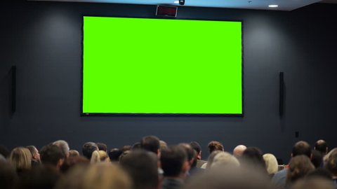 Public event. A huge space of the room is filled with persons from political or financial organization looking at green screen. Concept of common accessibility of information. Chroma key and advertise