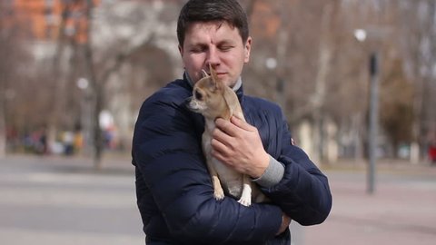 Portrait of man stroking chihuahua on his hands in park
