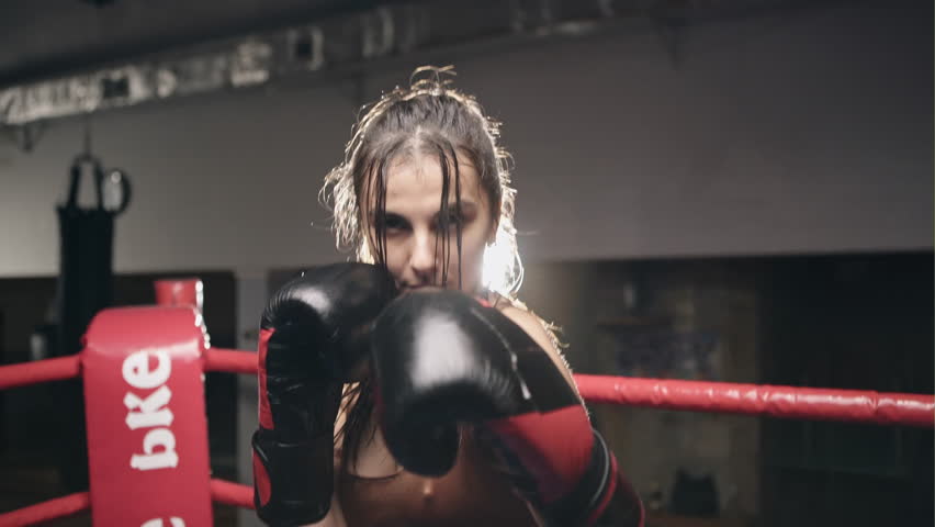 Fighter woman fist close up - boxer strikes into the side of the camcorder. Spectator video boxing. Strong aggressive young girl woman boxing in the ring as a symbol of feminism and successful women Royalty-Free Stock Footage #24560147