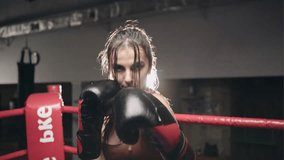 Fighter woman fist close up - boxer strikes into the side of the camcorder. Spectator video boxing. Strong aggressive young girl woman boxing in the ring as a symbol of feminism and successful women