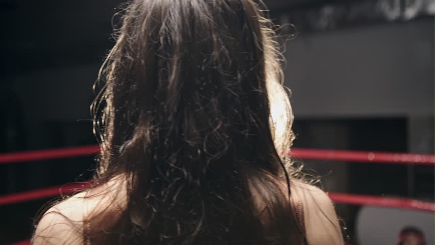 Sport boxing girl wearing black boxing gloves sitting in corner of boxing ring.