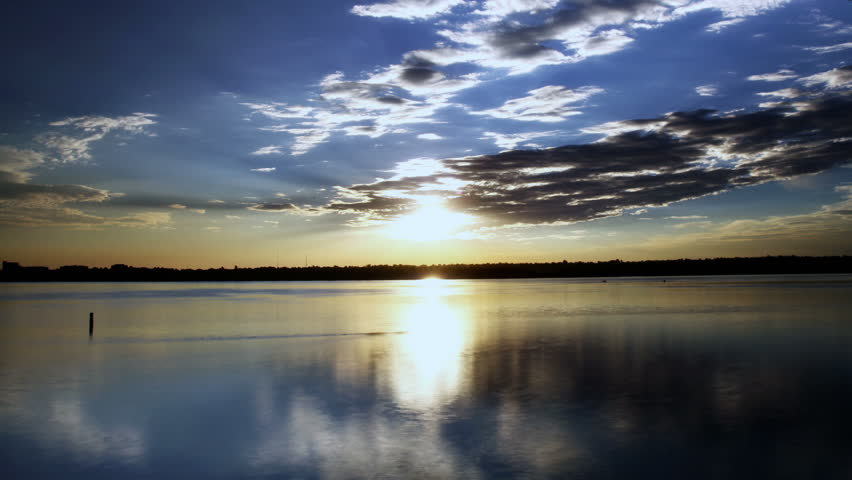 The morning sun dances behind clouds, reflected in the mirrored surface of a
