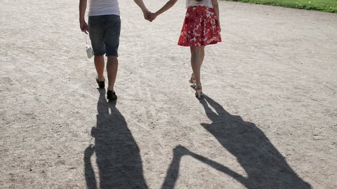 Young lovely couple walks in park at sunny day