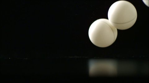 Ping-pong balls bouncing across a black background Stock Video