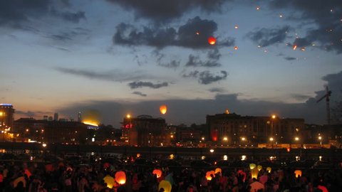 Many heavenly small lanterns fly to night sky against floating clouds, time lapse
