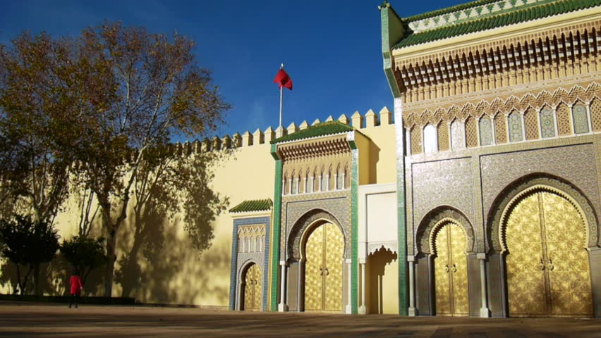 Left side of the Royal Palace of Fes (Dar el Makhzen), Morocco - golden doors, mosaics and red moroccan flag with wind. 