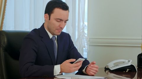 Worried businessman looking on smartphone and reading bad news