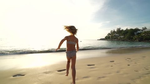 Little cute funny girl laughing and running on the beach