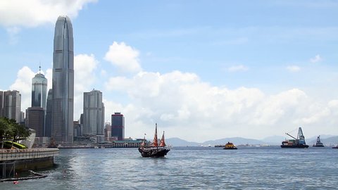 Chinese Junkboat sailing across Victoria Harbour and city skyline, Hong Kong.
