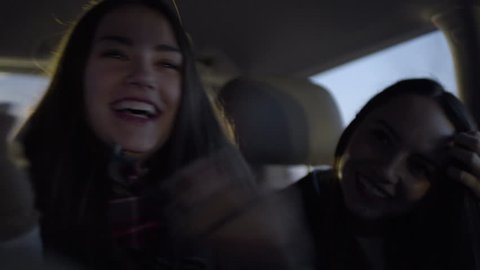 Fun Teen Girls Practice Funny Dance Moves Together In Back Seat Of Moving Car At Night