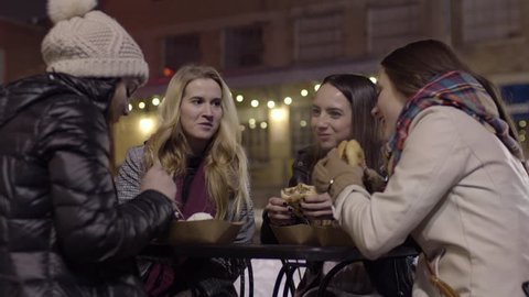 Group Of Friends Enjoy Girls Night Out At Outdoor Cafe, Latina Girl Tells Her Friends A Story, They Laugh