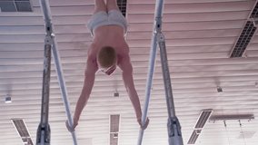 Gymnast performs routine on parallel bars HD gymnastics slow-motion video. Athlete training skills and doing swings acrobatic exercises: hand support, flip
