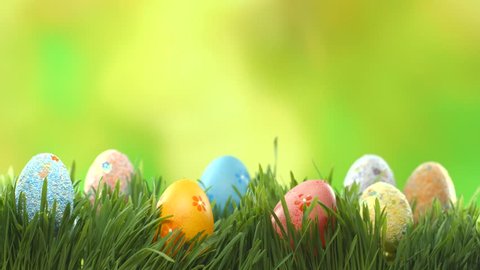 Easter colorful painted eggs on lawn grass over green blurred bokeh background. Spring Holiday nature scene. UHD video footage. Ultra high definition 3840X2160