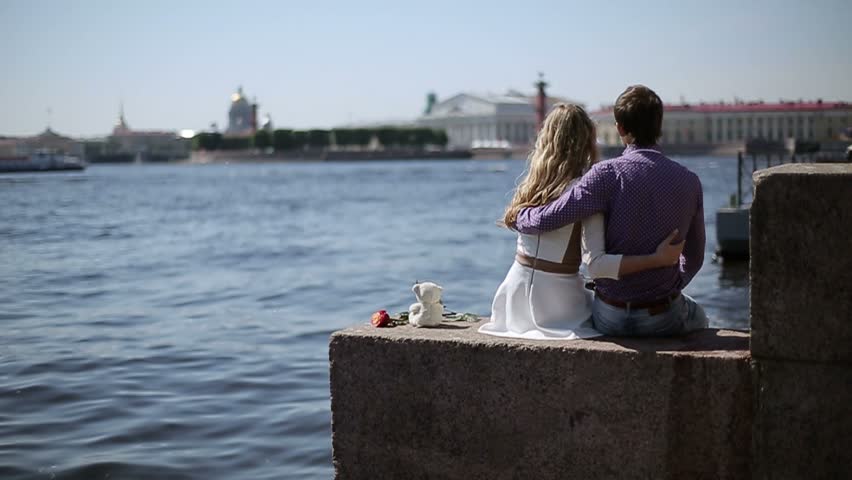 Lovely couple sitting on embankment at sunny day