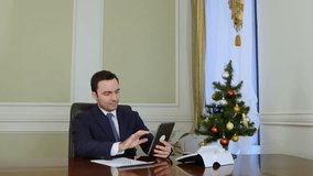 Businessman congratulates business partners with Christmas via internet with tablet