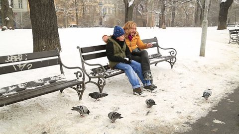Mother with son sitting on a park bench, a snowy winter day