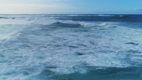 Aerial slow motion of beautiful sea waves. As the waves moves they create texture from white sea foam. Drone footage of seascape against sky. 