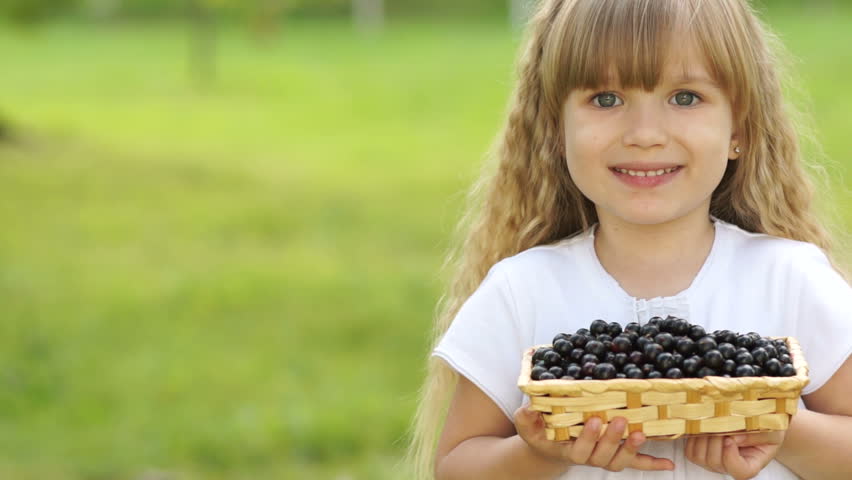 Closeup portrait of child holding a basket of black currant

