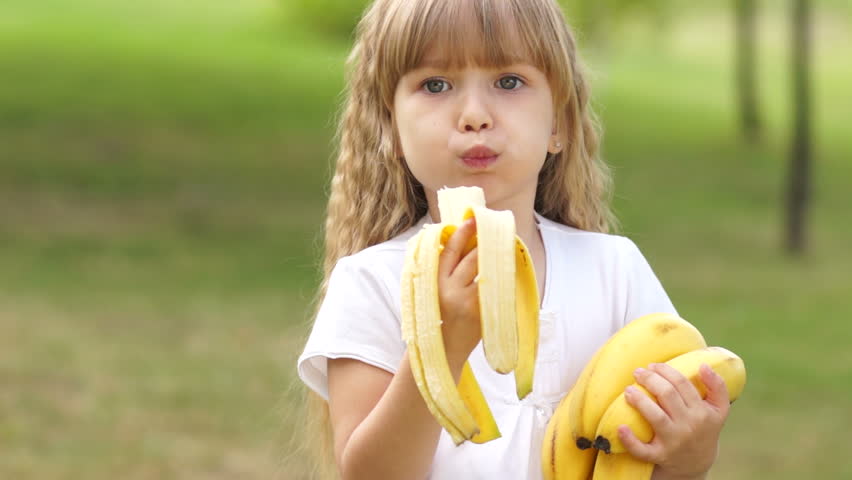 Child eating bananas outdoors
