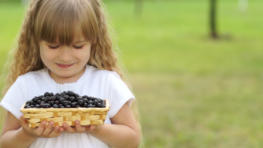 Close-up portrait of girl holding a basket of black currant
