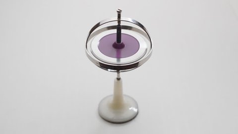 Gyroscope rotates on a light gray table.