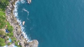 Aerial video : Flies over the coast of a tropical island, the stones are washed by waves, the top view, Thailand