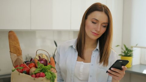 Woman came back home from grocery shopping texting on her cellphone