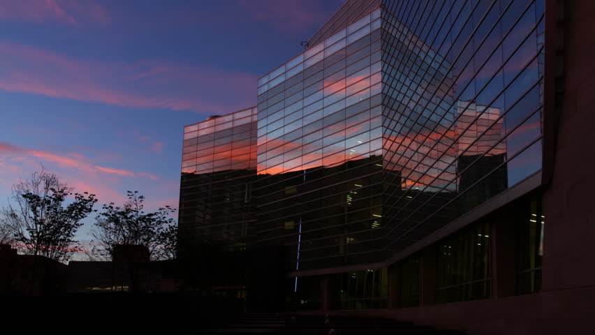 Reflections of clouds at sunrise in the windows of a contemporary office