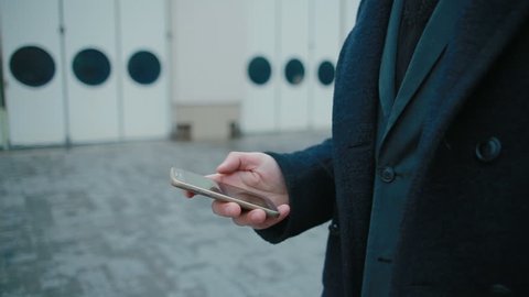 Close-up of a businessman's hand using a smartphone walking through the city. in slow motion
