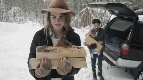Cute Couple Carry Firewood (From Back Of SUV) Into Cozy Mountain Cabin, In Snowy Utah Mountains : vidéo de stock