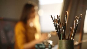Artist's studio. Paintbrushes with painter silhouette painting in background