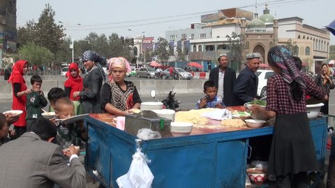 HOTAN - SEPTEMBER 10 2010: Uyghur people are ordering food from a local stand on the streets of Hotan, in China