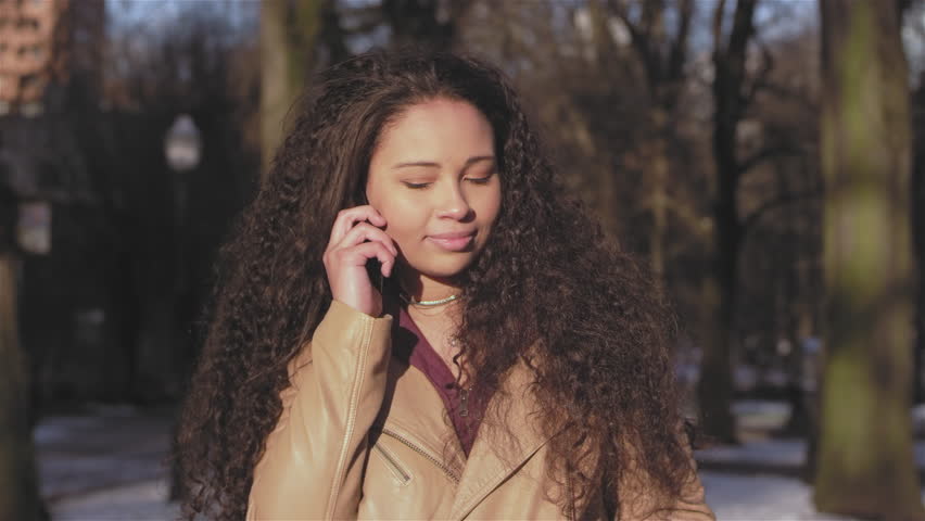 Portrait shot of a beautiful young woman taking a selfie on her phone while sitting on a wooden park bench