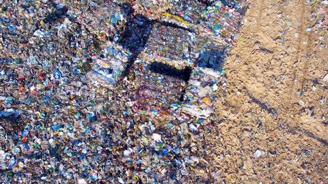 Piles of empty bottles, bags and other plastic in the garbage dump. Aerial.
