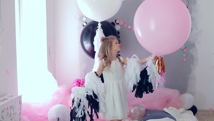 portrait of little baby girl smiling on the day of birth in a dress with colorful balloons. Excited kid celebrating her birthday