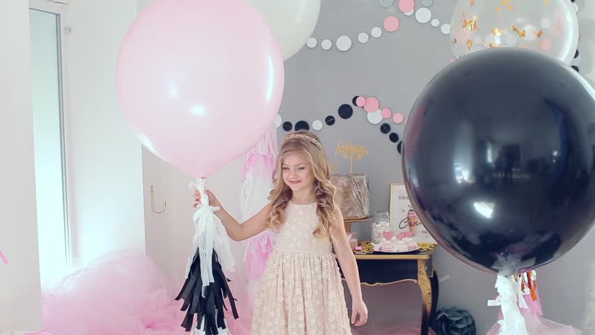 portrait of little baby girl smiling on the day of birth in a dress with colorful balloons. Excited kid celebrating her birthday