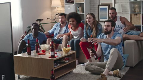 Zoom in of multi-ethnic group of friends celebrating victory of their team. They yelling, clapping hands and whistling while sitting in living room and watching TV match