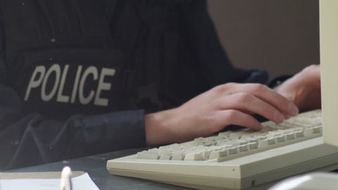 Police on keyboard filing reports close up