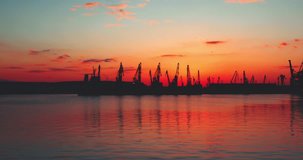 Burning sunset over sea port Varna and industrial cranes