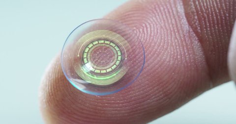 Macro shot of a finger holding a contact lens technology with a chip to see better in both eyes and increase diopters. Concept: eye examination, optical, immersive technology