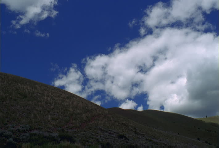 Time-lapse clouds above a grassy hillside
