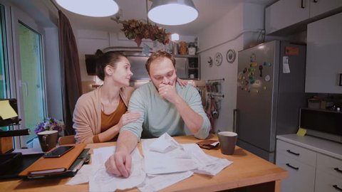 Worried couple looking at their bills in the kitchen at home. Man and woman calculating domestic accounts.