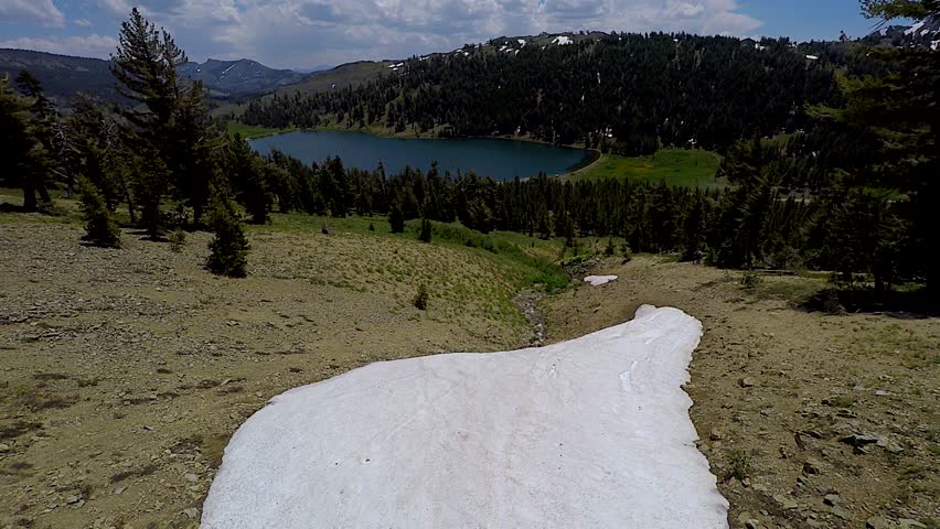4k UHD Aerial tracking back from snow capped mountain with calm mountain lake below in Arnold California in the Yosemite National Park as camera tracks away from mountain