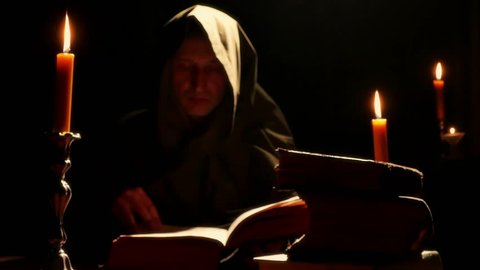 Monk reads the old liturgical book in the monastery cell under candlelight