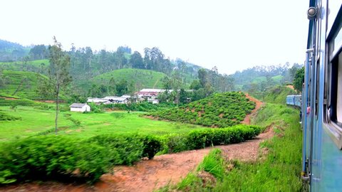 NUWARA ELIYA, SRI LANKA - MAY 6, 2016: Train passing small village with colorful houses at tea plantations. Traditional farmers housing in Sri Lanka