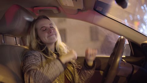 Profile Of Young Female Driver, She Dances And Sings In Car At Red Light, Light Turns Green And She Smiles At Her Passenger And Drives