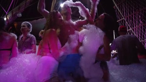 ALANYA - AUG, 15, 2015: Two woman dance around man (wits model releases) on foam party on ship in stroboscope light, mobile phone video. Foam show - main action, for which there is ship at night.