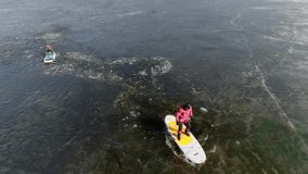 Aerial view of two athletes on the SUP. Winter. Ice. Slowmotion.